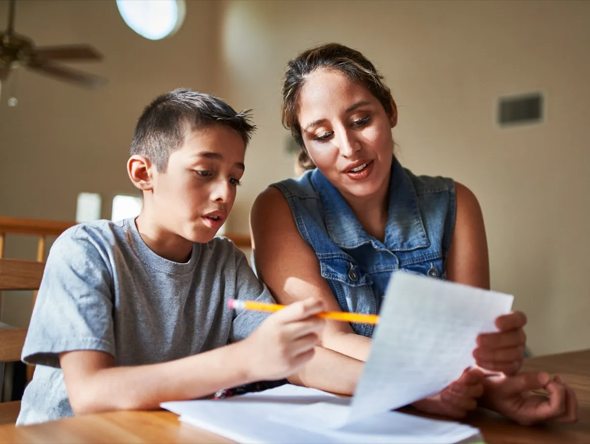A mother helping her son with schoolwork at the kitchen table