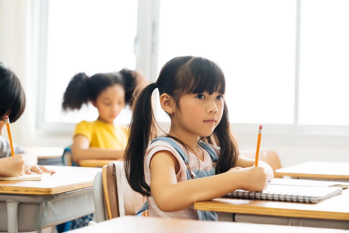 Young students writing at their desks in a classroom