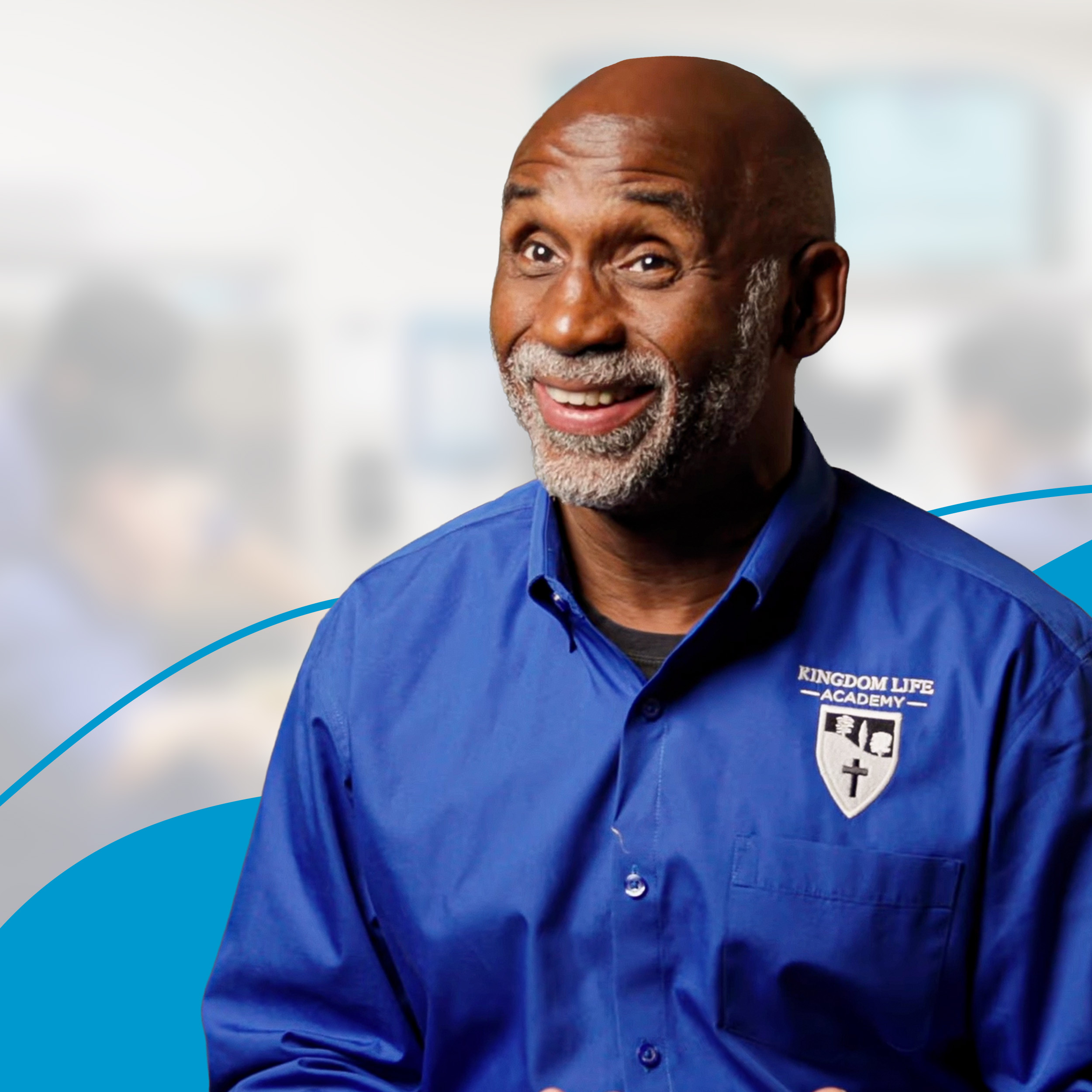 Smiling male wearing a blue Kingdom Life Academy shirt.