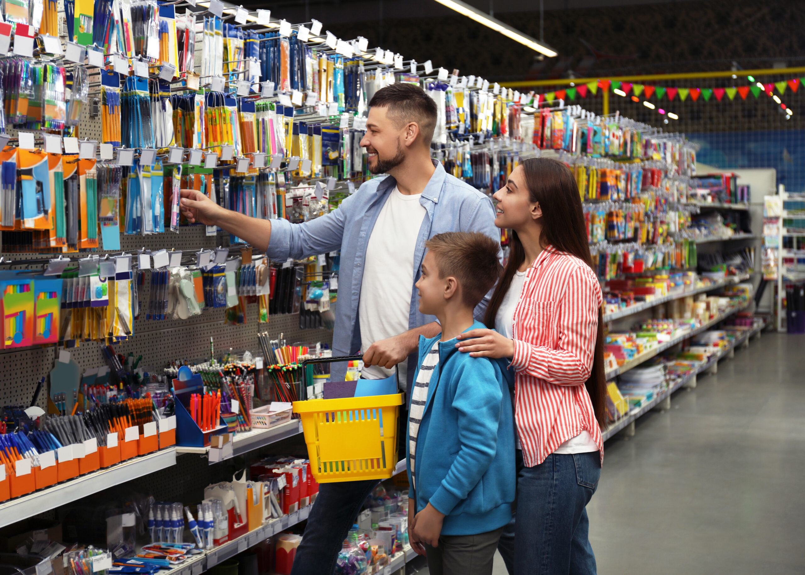 Family shopping for school supplies in a store, selecting items like pens and notebooks