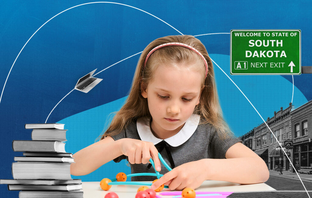 A girl builds a molecule model at her desk, with a South Dakota welcome sign in the background.